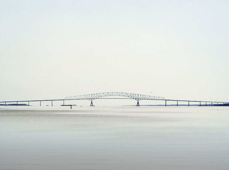 Distant view of a truss bridge spanning a broad body of water