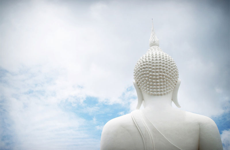 White Buddhist statue against cloudy blue sky