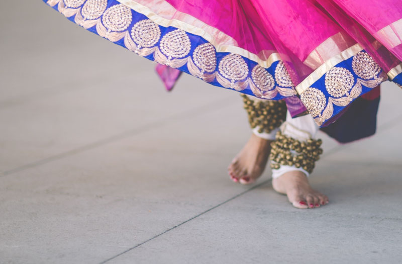 The feet of a dancer under a swirling, bright pink skirt